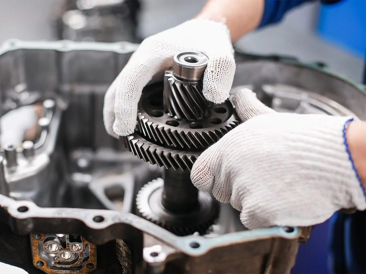 A technician in work gloves fitting a gear set into an open transmission case